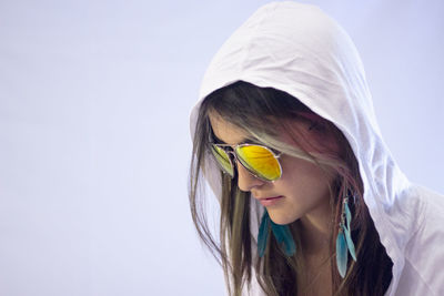 Close-up of woman wearing sunglasses against white background