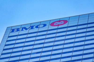 Low angle view of text on building against clear blue sky