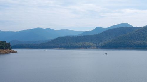 Scenic view of sea by mountains against sky