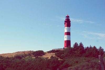 Low angle view of lighthouse by building against sky