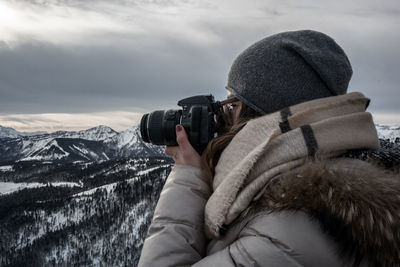Close-up of woman photographing on snow against sky