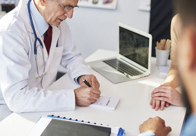 Midsection of man using laptop on table