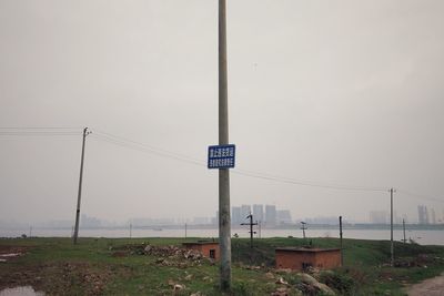 Road sign on field against sky