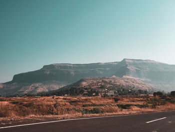 Road by mountains against clear sky