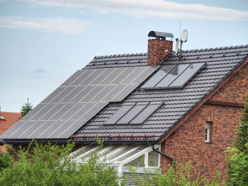 Large solar panels on roof of house. horizontal orientation, blue sky, gray panels on brown roof.