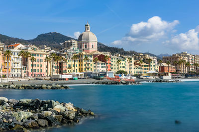 Buildings by sea against sky in city