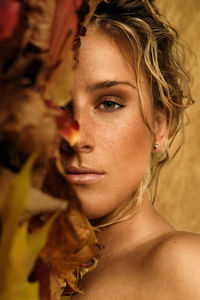 Close-up portrait of woman face covered with autumn leaves