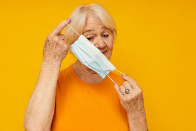 Midsection of woman holding tape measure against yellow background