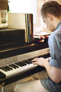 Side view of man playing piano at home