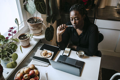 Young female entrepreneur sitting with laptop while working from home