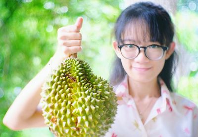 Portrait of smiling young woman holding durian