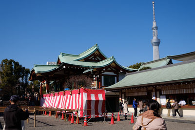 Group of people in front of building against clear blue sky