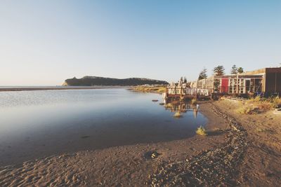 Scenic view of beach by sea against clear sky
