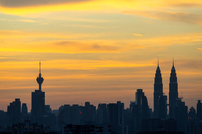 Petronas and kl tower in city against cloudy sky during sunset