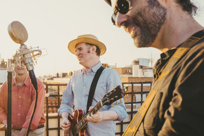 Man wearing sunglasses singing by microphone standing against sky