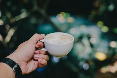 Cropped image of man hand holding coffee cup outdoors