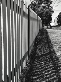 Empty footpath by fence against sky