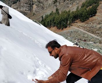 Side view of young man holding snow