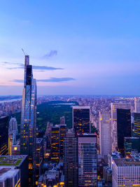 Illuminated buildings in city against sky during sunset