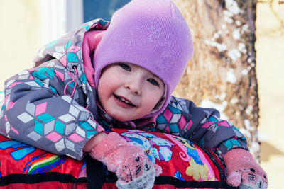 Child in violet clothes having fun on tubing around the house. winter activities for children