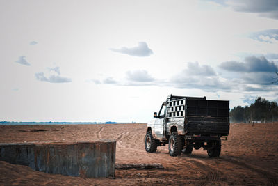 Tractor on field by sea against sky