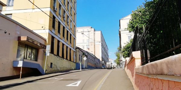 Road amidst buildings against clear sky