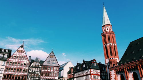 Low angle view of buildings against blue sky on sunny day