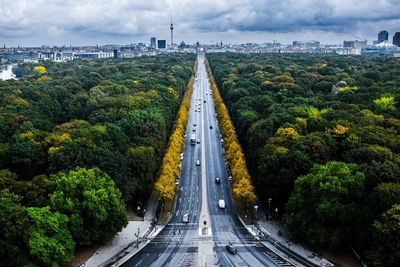 Road amidst trees in city against sky