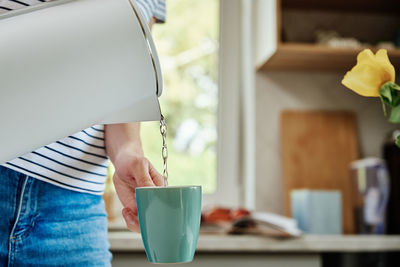Woman pouring water from kettle for brewing tea