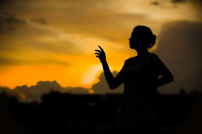 Silhouette man standing against orange sky during sunset