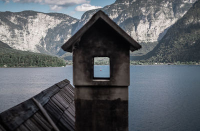 Built structure by lake against mountains