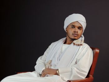 Low angle view of young woman sitting against black background