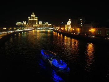 Illuminated bridge over river in city at night