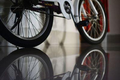 Cropped image of bicycle with reflection on floor