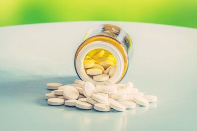 Close-up of medicine bottles on table against green background