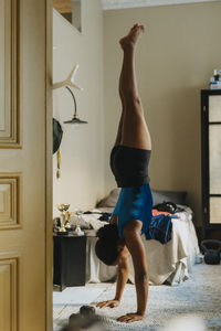 Female athlete doing hand stand in bedroom at home