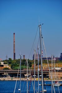 Sailboats in harbor against clear blue sky