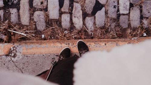 Low section of man standing on stone wall