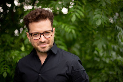 Portrait of young man standing against plants