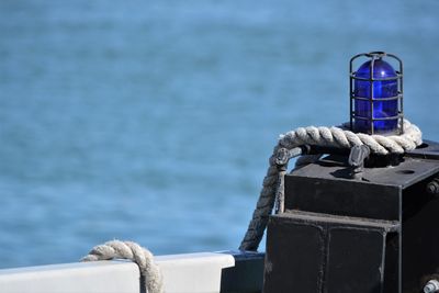 Close-up of rope tied on wooden post against sea