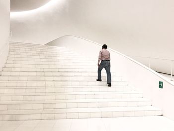 Rear view of man moving up on steps in building