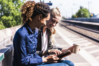 Happy coworkers using tablet pc at station platform