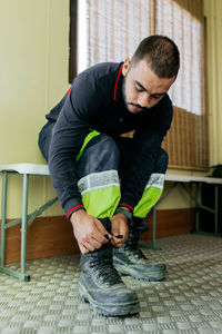 Seated firefighter buckling his boots before starting work in the metal-floored men's locker room