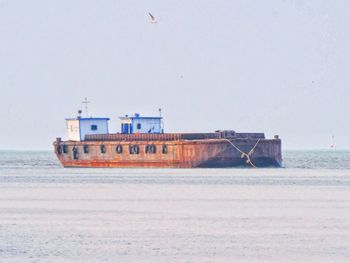 Ship sailing on sea against clear sky