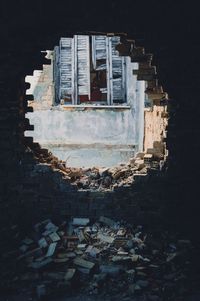 Broken window seen through hole in wall