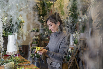 Senior woman arranging flowers at flower shop desk