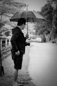 Man with umbrella standing on wet rainy day in city