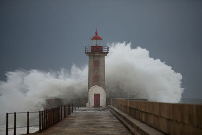 Lighthouse by sea against sky