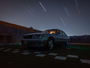 Cars on illuminated road against sky at night