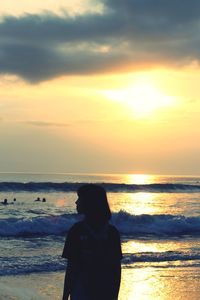 Rear view of silhouette man standing at beach during sunset